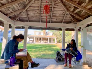 A student and teacher sit beneath a lantern in the gazebo for a Mandarin Chinese lesson